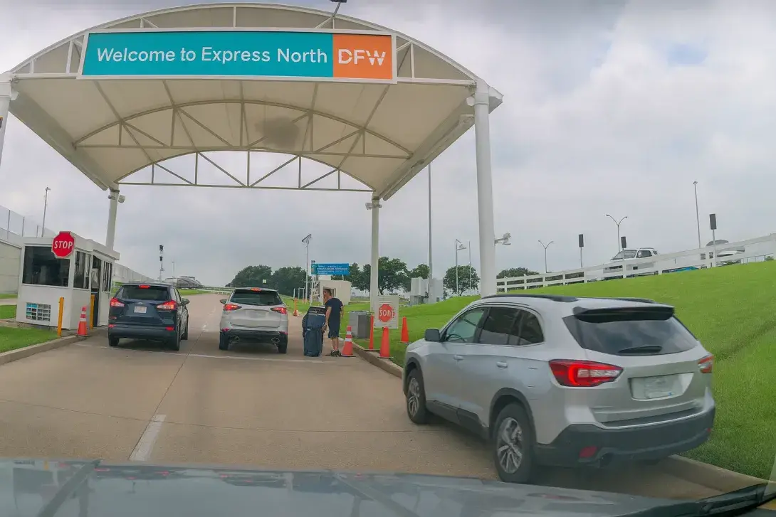 Entrance to Express North Parking at DFW airport with cars and an attendant booth